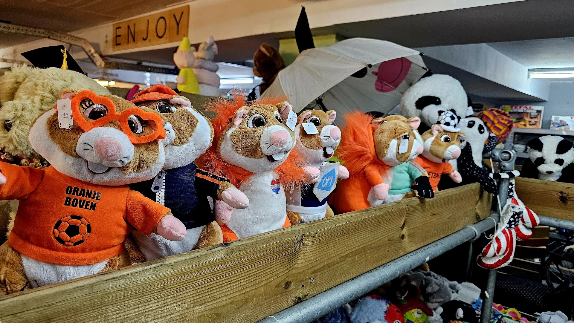 Uitgestalde pluchen speelgoed en knuffels in verschillende kleuren op een houten schap in de winkel