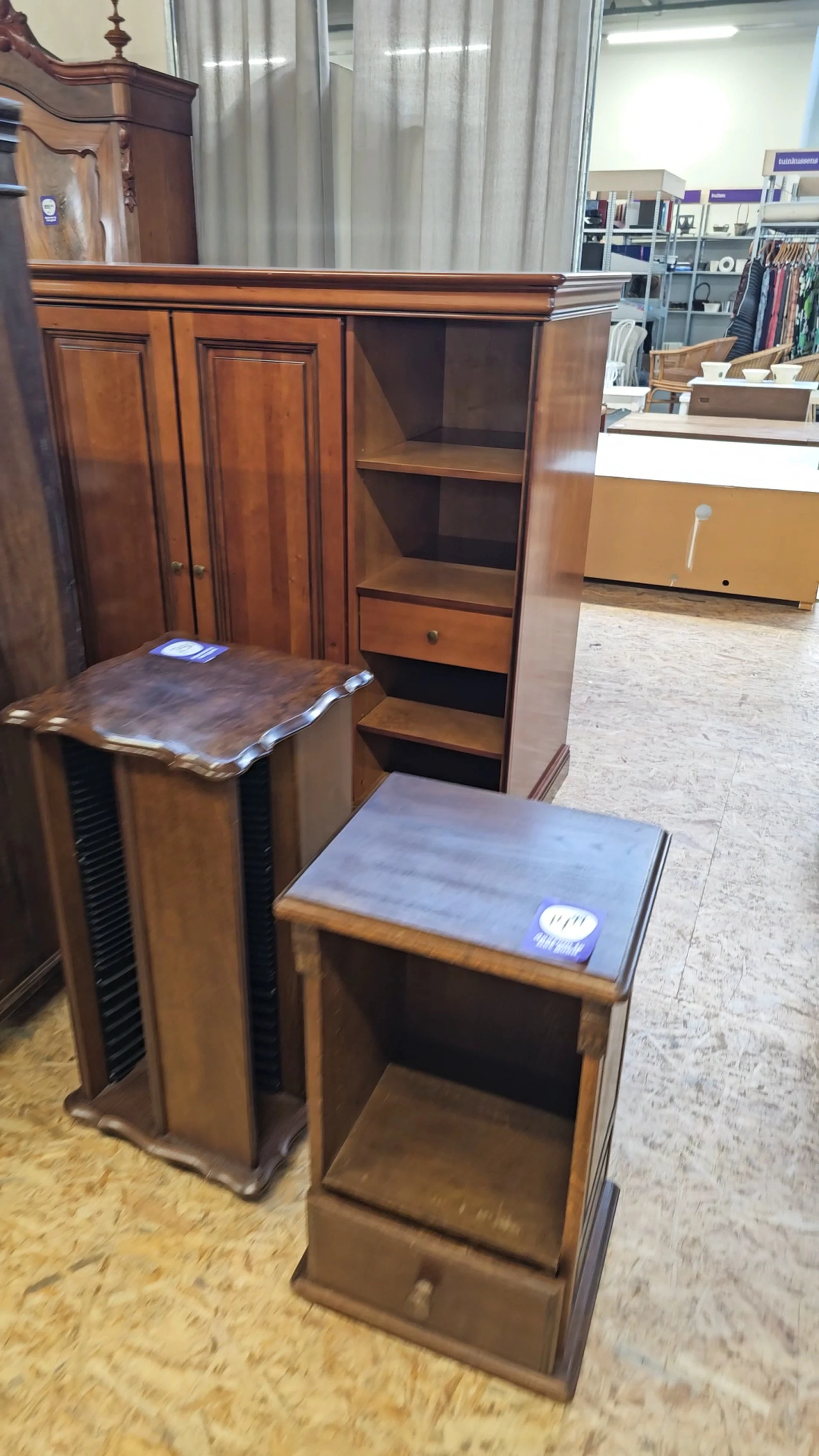 Twee houten meubels met blauwe zittingen op de winkelvloer, op de achtergrond kasten en stellingen