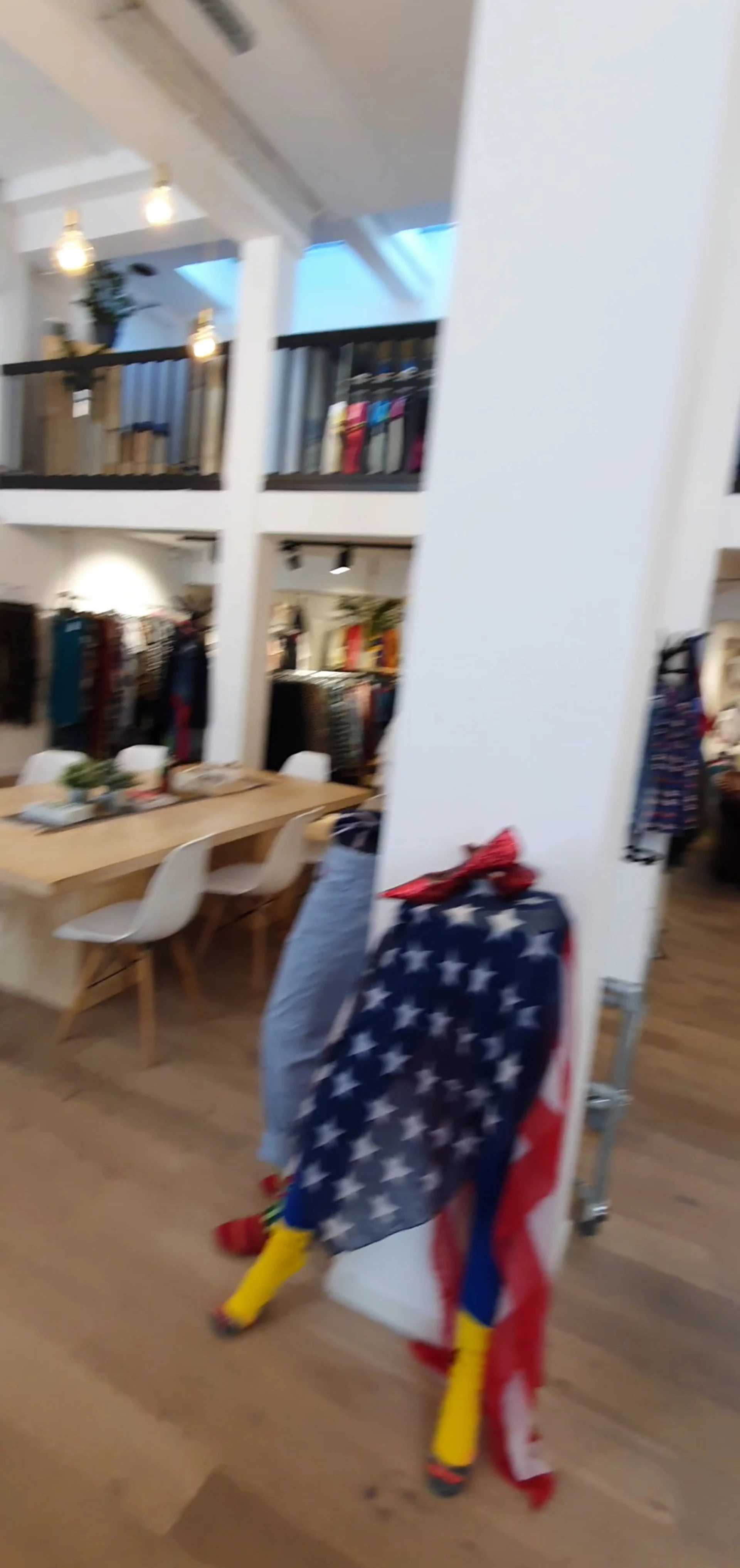 Winkelinterieur met spiegel, houten tafel, witte stoel en kledingrekken op de achtergrond