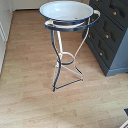 Ronde bijzettafel met wit blad en zwart metalen voetwerk op houten vloer