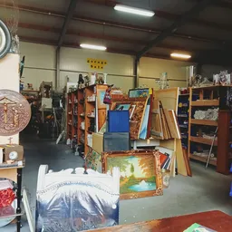 Winkelvloer met diverse meubels, schilderijen en decoratie, met geel bord 'Garage Sale' boven
