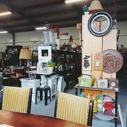 Winkelvloer van kringloopwinkel met diverse meubels, huishoudartikelen en decoratieve spullen op stellingen en planken