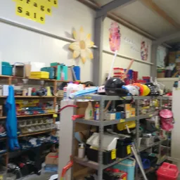 Rommelige kringloopwinkel met stellingen vol spullen, dozen en diverse artikelen