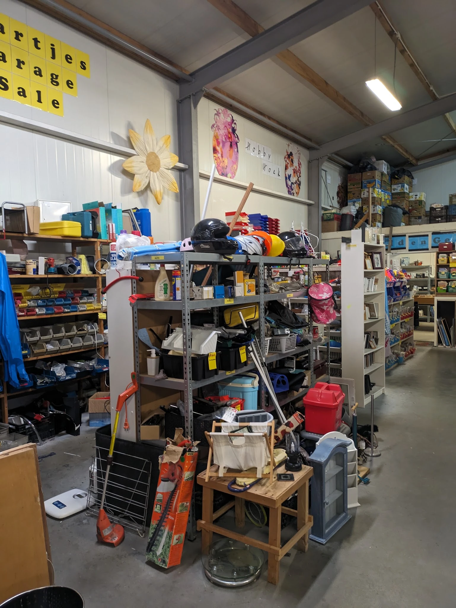 Volle stellingen en rekken met diverse goederen in een kringloopwinkel