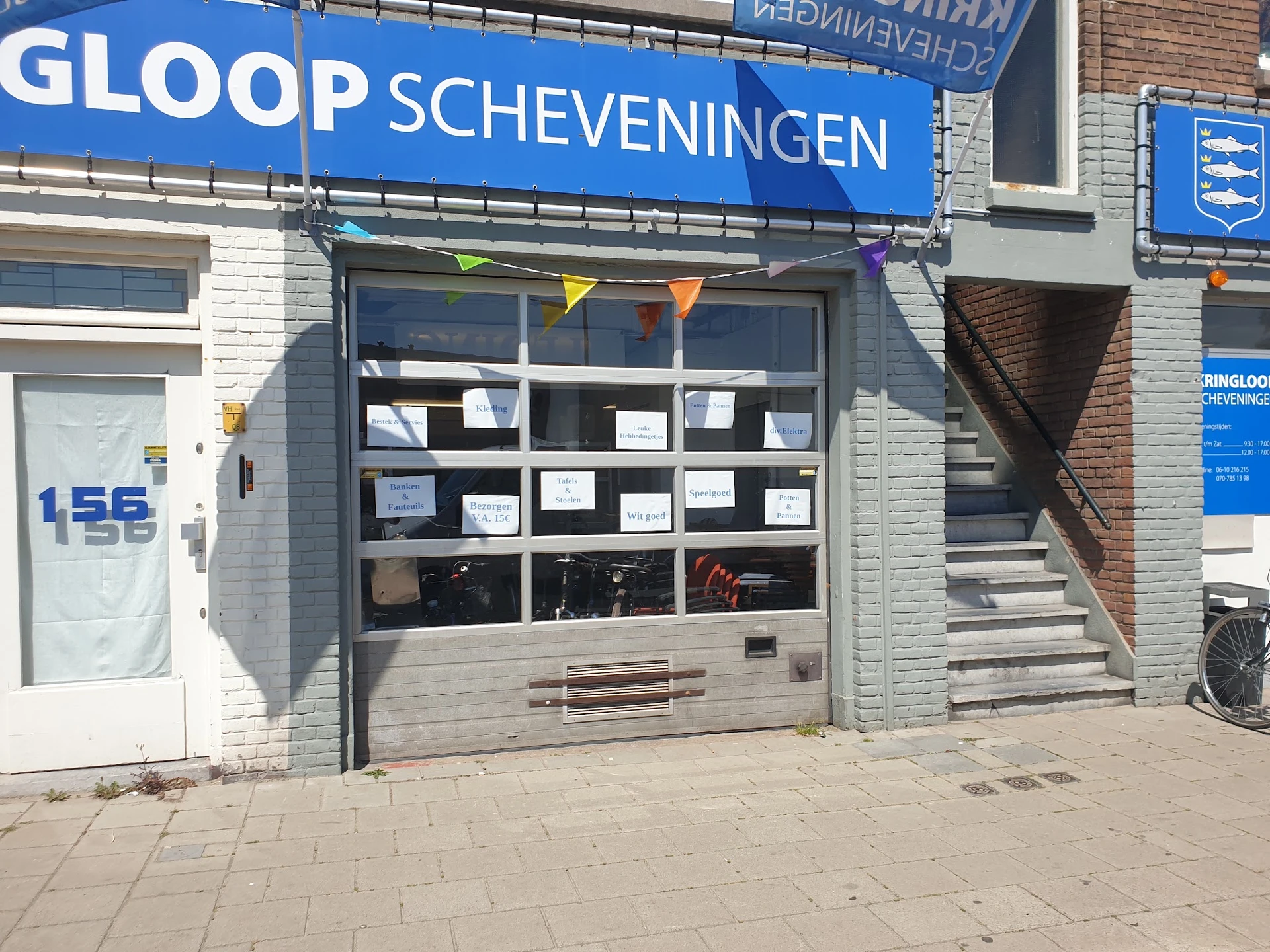 Winkelgevel van Gloop Scheveningen met donkergrijs/zwarte puiframen, witte bakstenen gevel en blauwe winkelnaambord