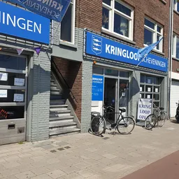 Gevel van Kringloop Scheveningen met blauwe uithangbord, etalageruiten en fietsen ervoor