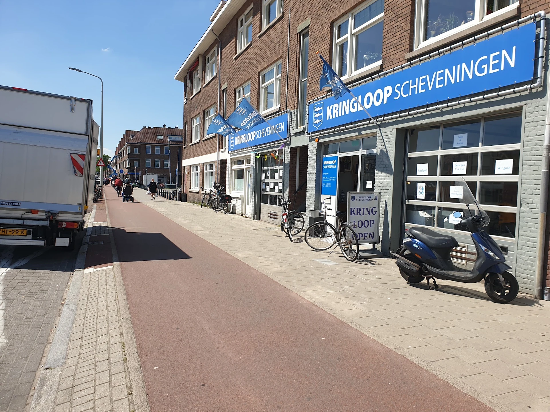 Gevel van Kringloop Scheveningen aan de Westduinweg met blauwe uithangbord, winkelpui en fietsen ervoor