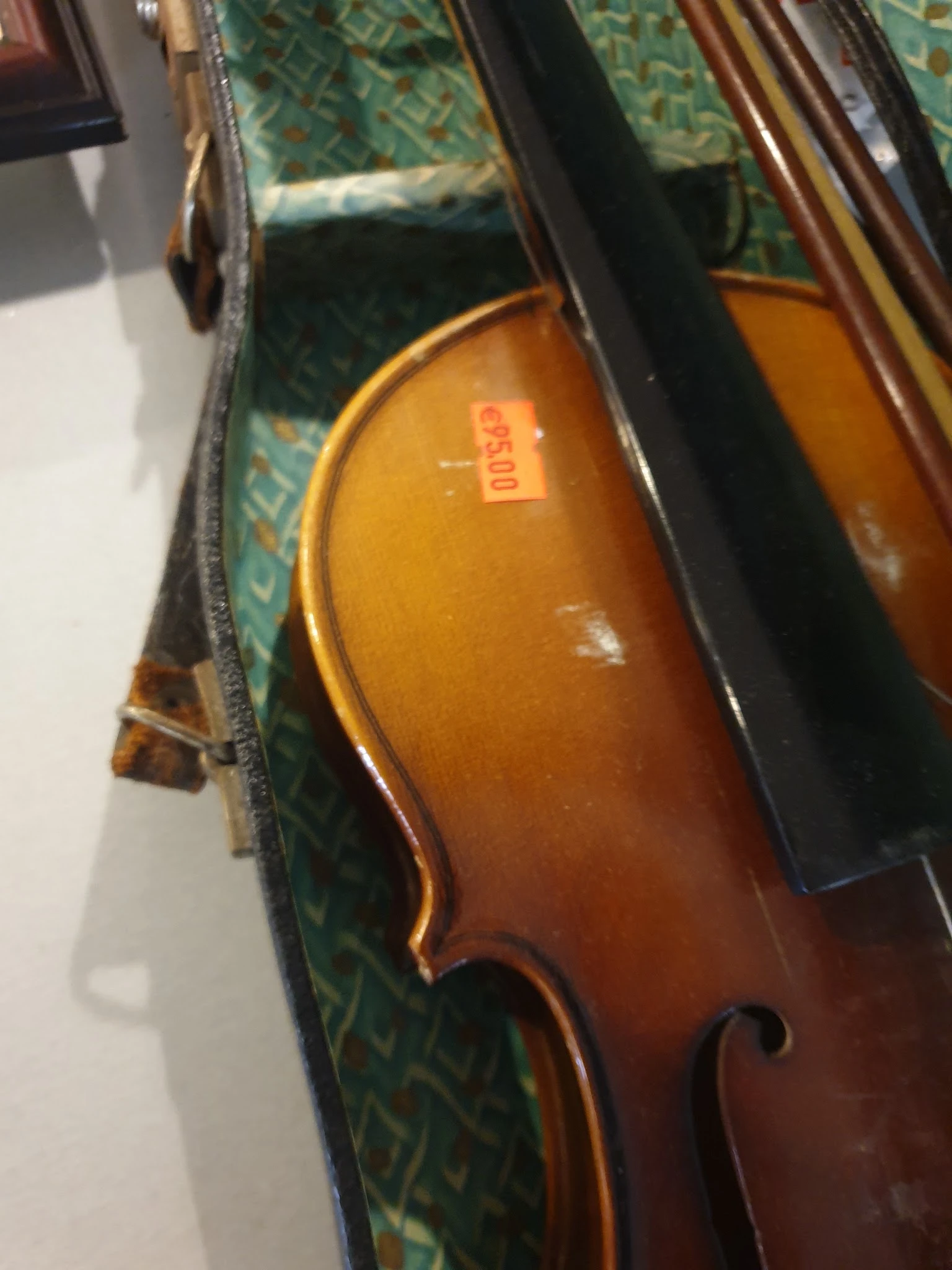 Close-up van een houten cello met bruine glans in een zwarte kist