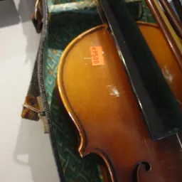 Close-up van een houten cello met bruine glans in een zwarte kist