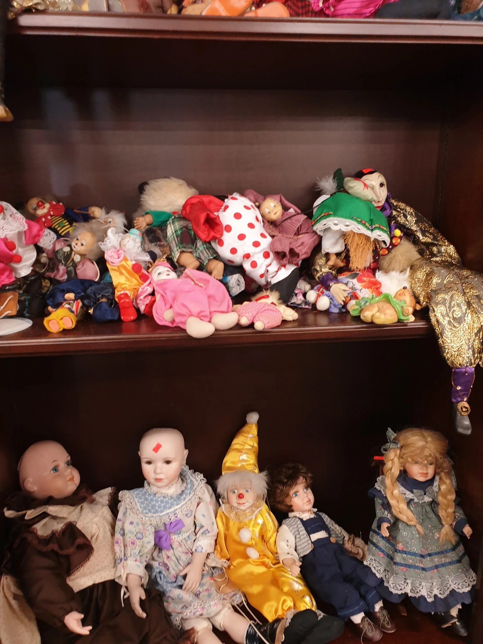 Twee planken vol met vintage poppen, knuffels en speelgoed in verschillende kleuren en stijlen