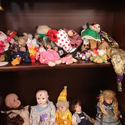 Twee planken vol met vintage poppen, knuffels en speelgoed in verschillende kleuren en stijlen