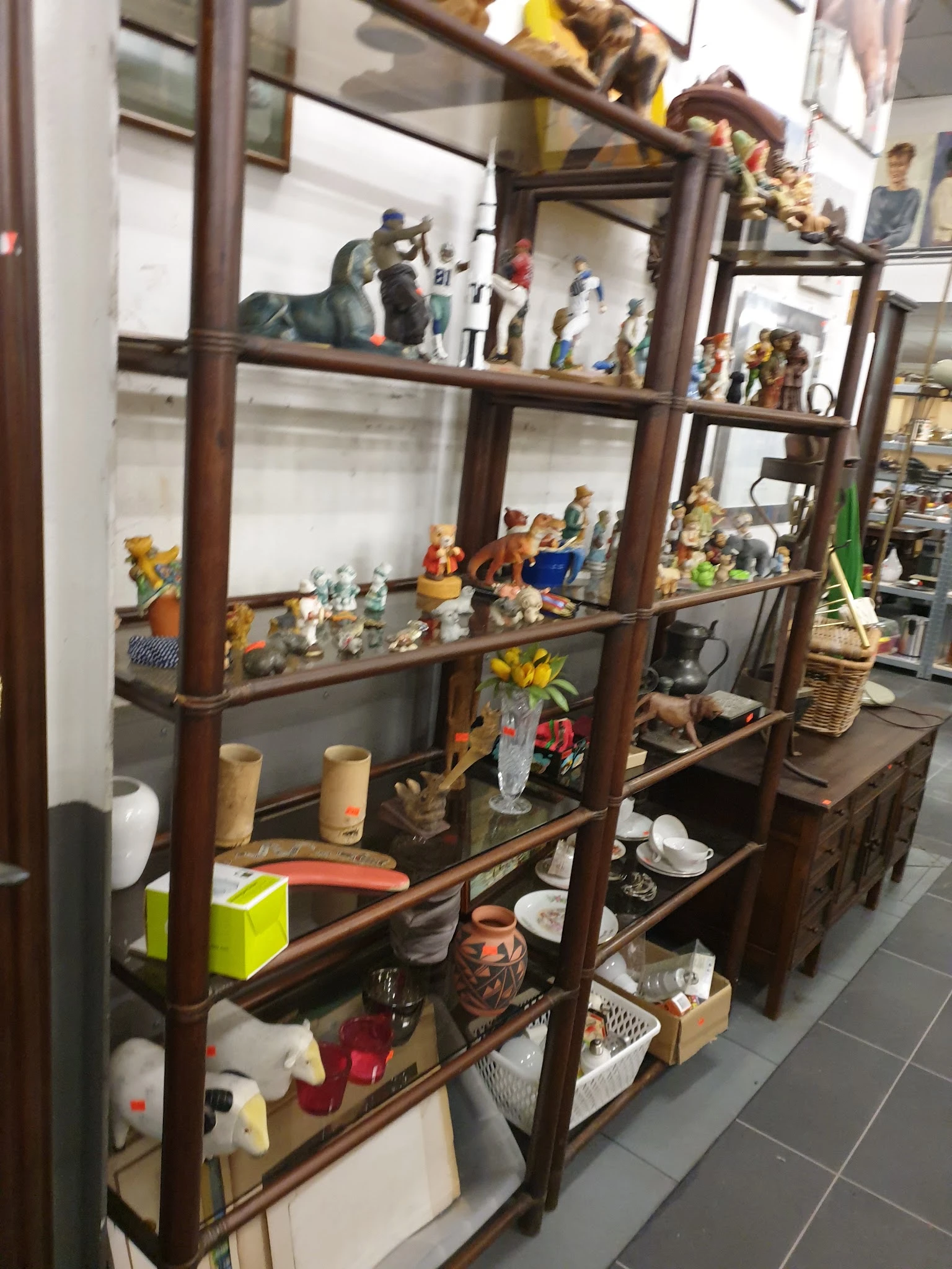 Houten vitrinekast met diverse decoratieve items, beeldjes, servies en huishoudartikelen uitgestald op meerdere niveaus