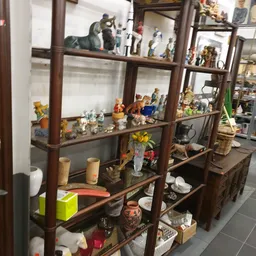 Houten vitrinekast met diverse decoratieve items, beeldjes, servies en huishoudartikelen uitgestald op meerdere niveaus