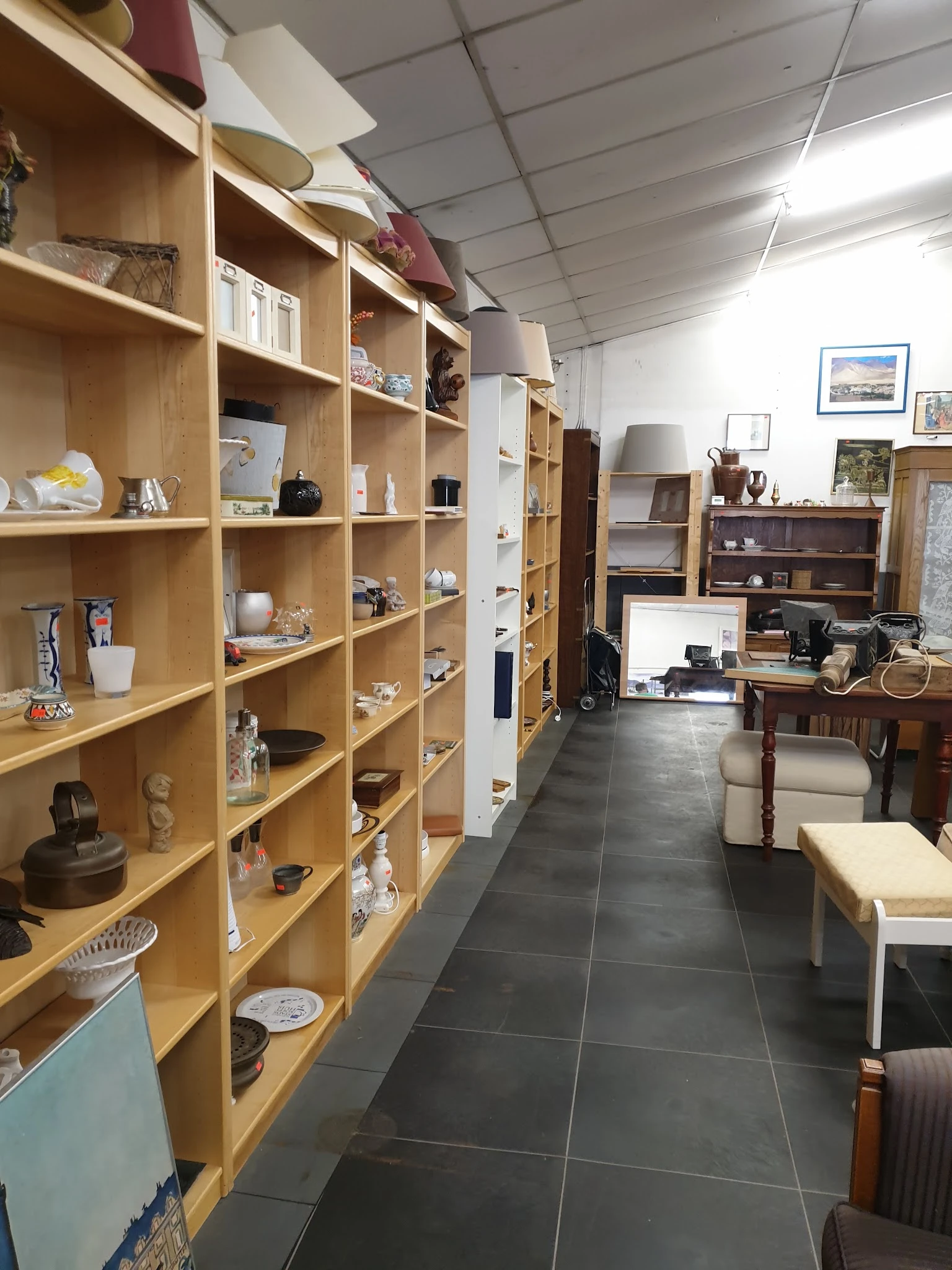 Winkelvloer met houten stellingen vol decoratieartikelen, meubels en spullen