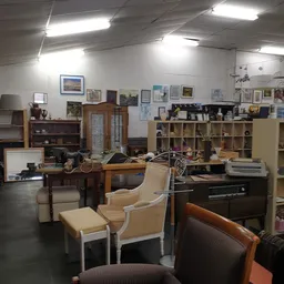 Winkelvloer met meubels, stellingen, kunstwerken aan muur en diverse tweedehandsspullen