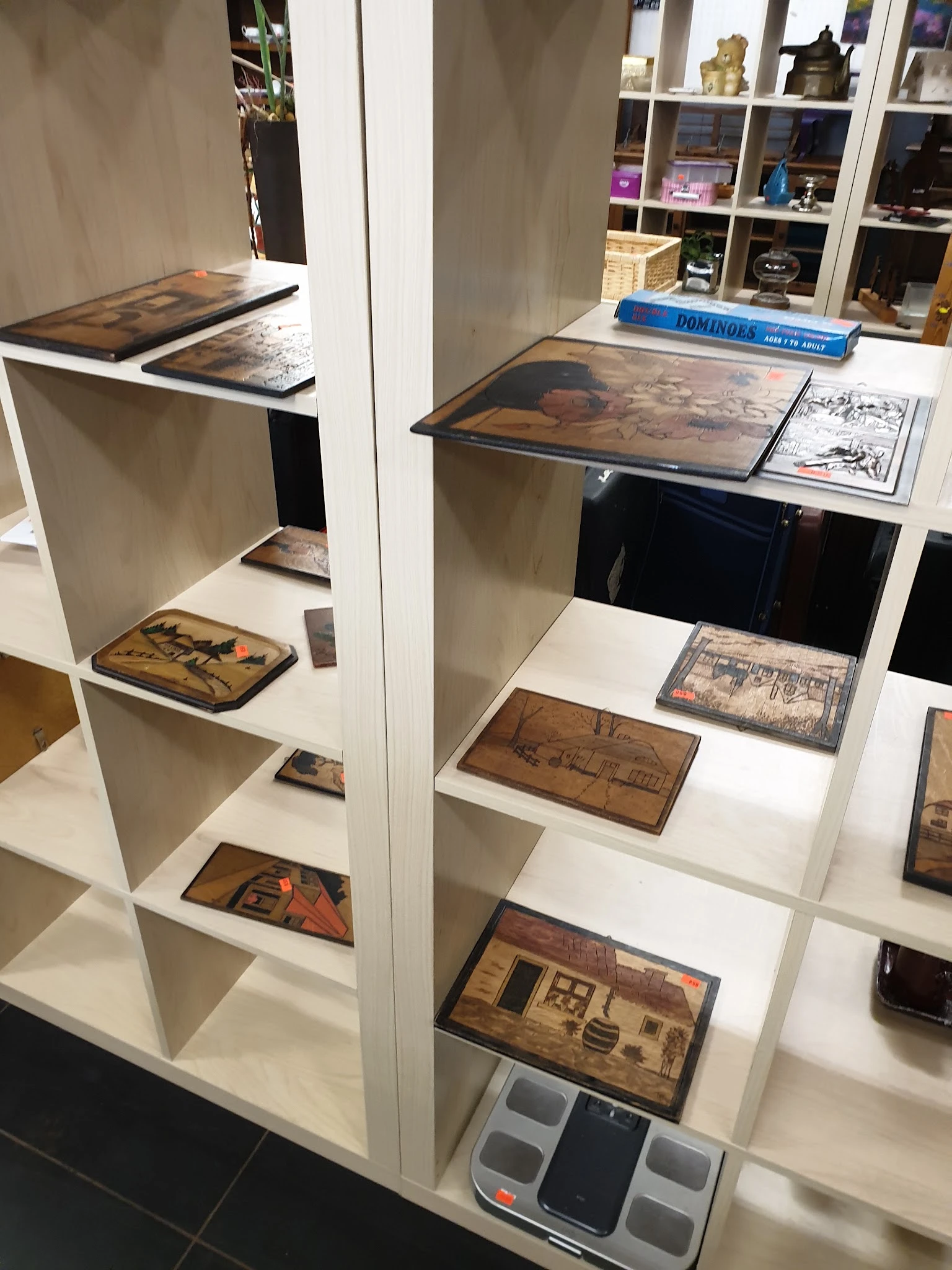 Open stellingen met houten kistjes en dozen met antieke afbeeldingen en teksten, netjes uitgestald op witte planken