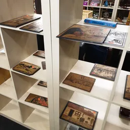 Open stellingen met houten kistjes en dozen met antieke afbeeldingen en teksten, netjes uitgestald op witte planken