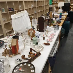 Tafel vol tweedehands huishoudartikelen, glaswerk, servies, houten gereedschap en decoratieve voorwerpen