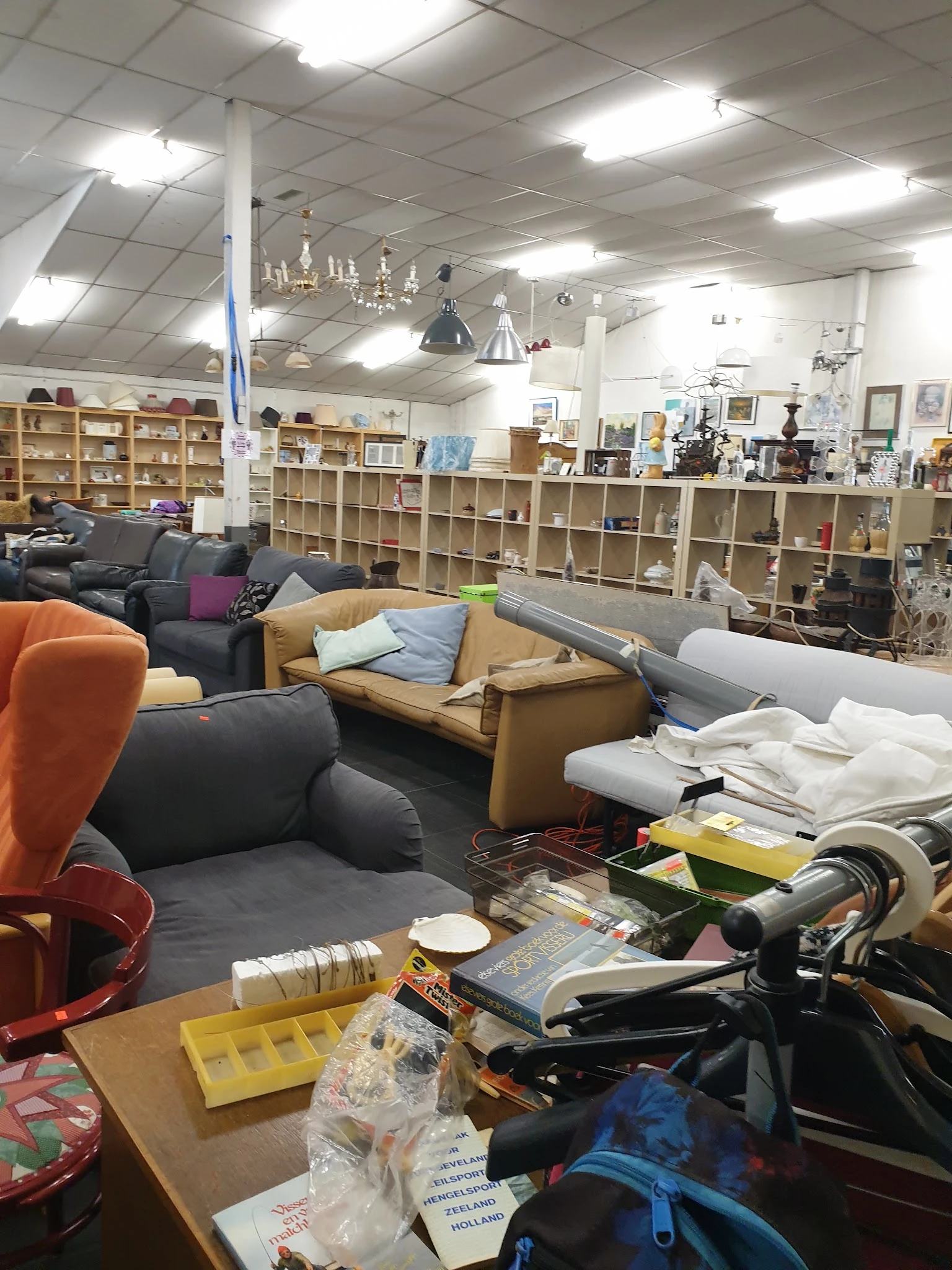Winkelinterieur met toonbanken, zitmeubels, stellingen vol spullen en diverse tweedehandsartikelen