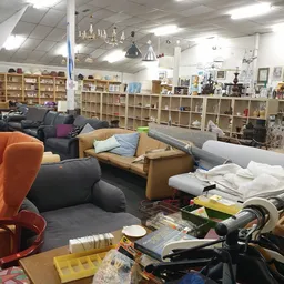 Winkelinterieur met toonbanken, zitmeubels, stellingen vol spullen en diverse tweedehandsartikelen