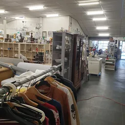 Overzicht van de winkelvloer met stellingen, kledingrekken, vitrines en diverse tweedehands spullen