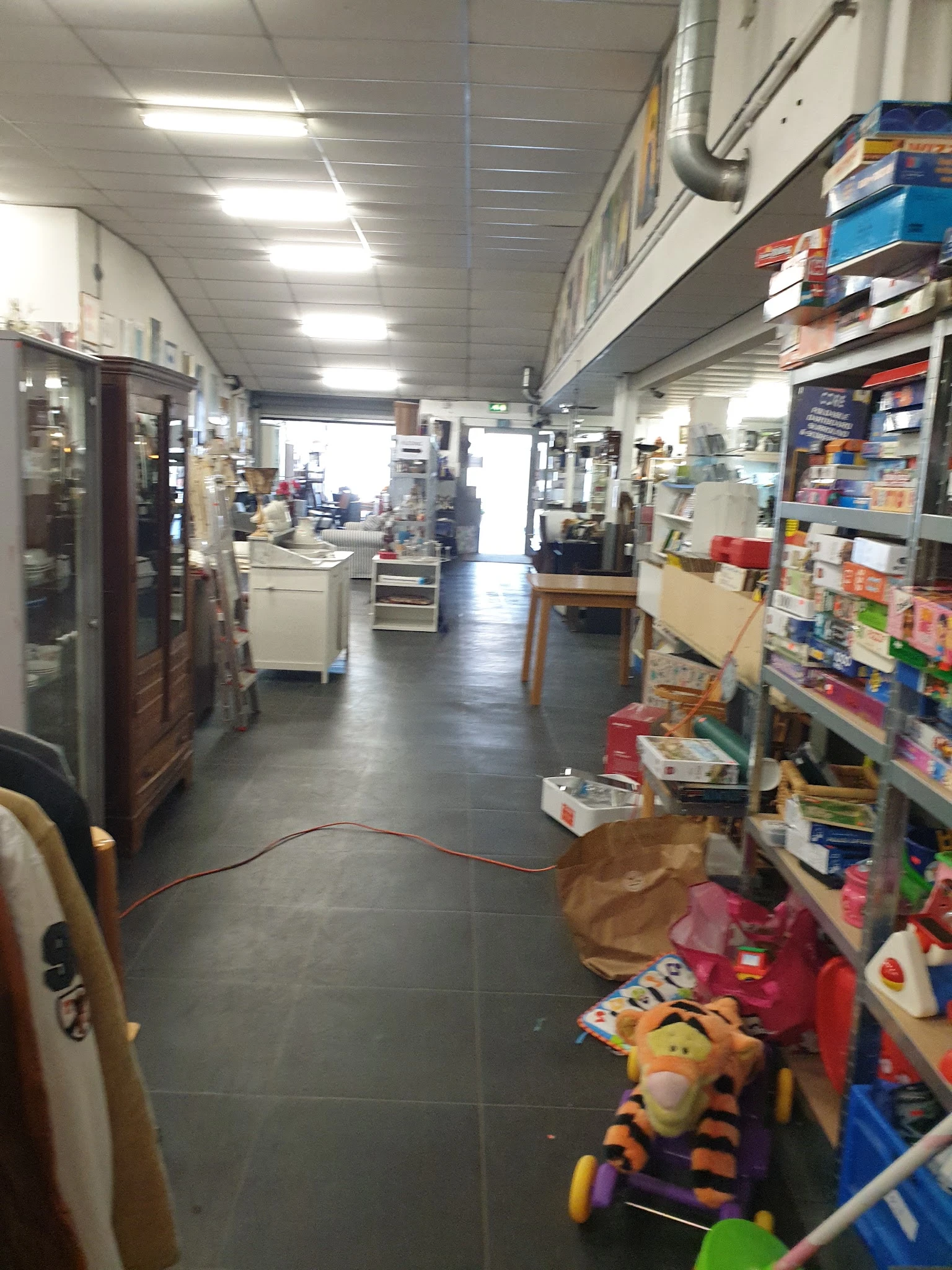 Winkelvloer van kringloopwinkel met stellingen, kasten en diverse tweedehands spullen aan beide zijden
