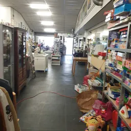 Winkelvloer van kringloopwinkel met stellingen, kasten en diverse tweedehands spullen aan beide zijden