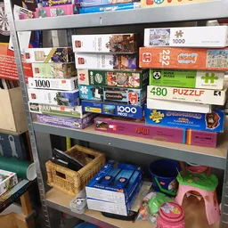 Stellingkast met stapels puzzels en bordspellen in verschillende formaten en kleuren