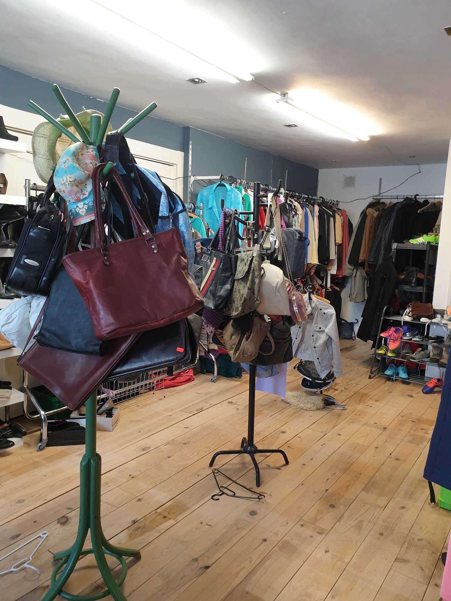 Winkelinterieur met tassen en kleding op hangers en stellingen, houten vloer