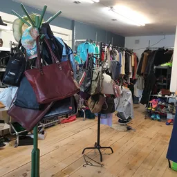 Winkelinterieur met tassen en kleding op hangers en stellingen, houten vloer