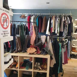 Kledingrekken en stellingen met tweedehands kleding, schoenen en accessoires