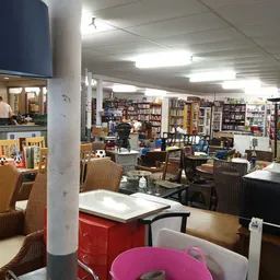 Winkelvloer met boeken in kasten, zithoeken met stoelen en tafels, diverse meubels en spullen