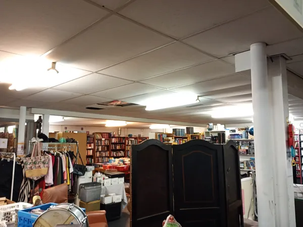 Winkelvloer met kledingrekken, boeken en huishoudartikelen onder fluorescerend licht
