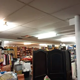 Winkelvloer met kledingrekken, boeken en huishoudartikelen onder fluorescerend licht
