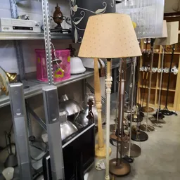 Stellingen met tweedehands huishoudartikelen en een tafellamp met beige kap op voorgrond