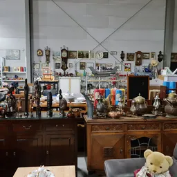 Winkelbinnenkant met antieke meubels, kasten, decoratieve items en diverse gebruiksartikelen op stellingen en toonbanken
