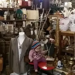 Kringloopwinkelinterieur met mannequin, decoratieve objecten, kasten en diverse spullen op stellingen