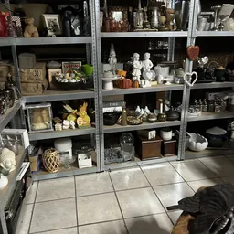 Metalen stellingen vol met decoratieve items: beeldjes, vazen, kaarsen, manden en huisraad in verschillende stijlen