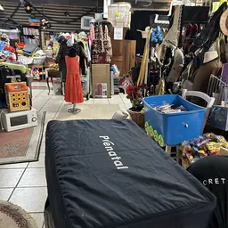 Winkelvloer met uitgestalde kleding op mannequins, rekken en dozen met goederen in een kringloopwinkel