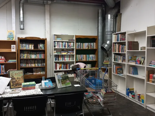 Boekenkasten en stellingen met boeken in een kringloopwinkel, winkelwagen op de vloer