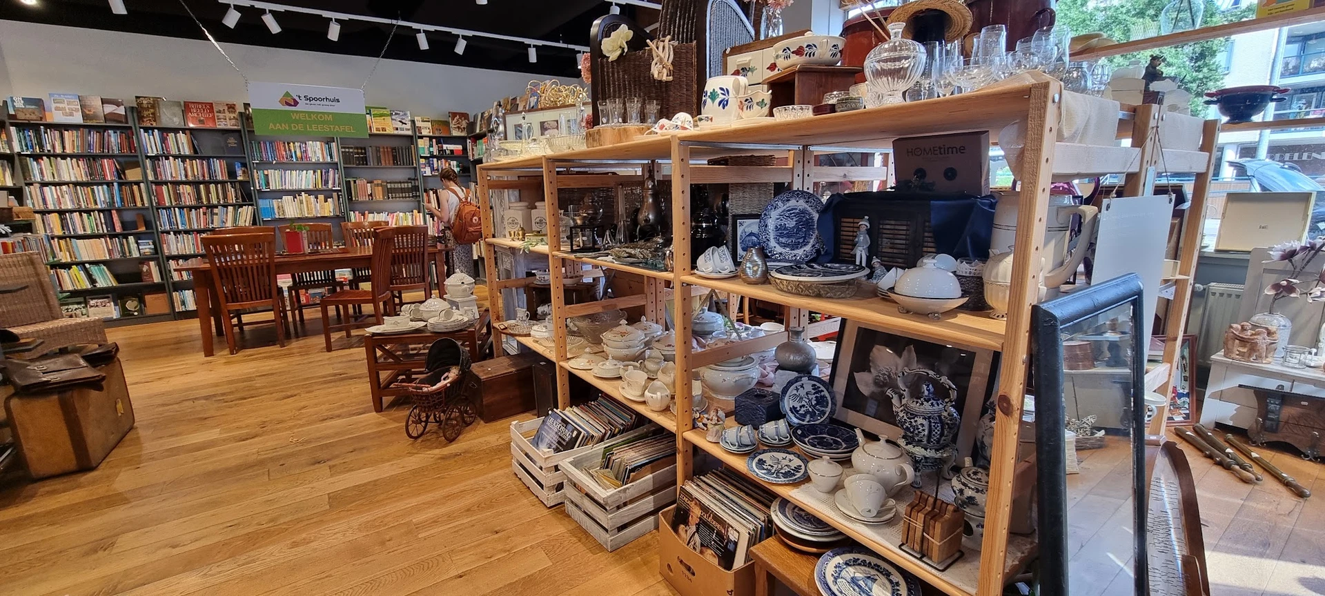 Houten stellingen met serviesgoed, borden en decoratieve items in een kringloopwinkel