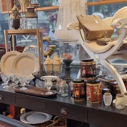Uitgestalde vintage serviesgoed, glazen en decoratieve huishoudartikelen op een donkere toonbank