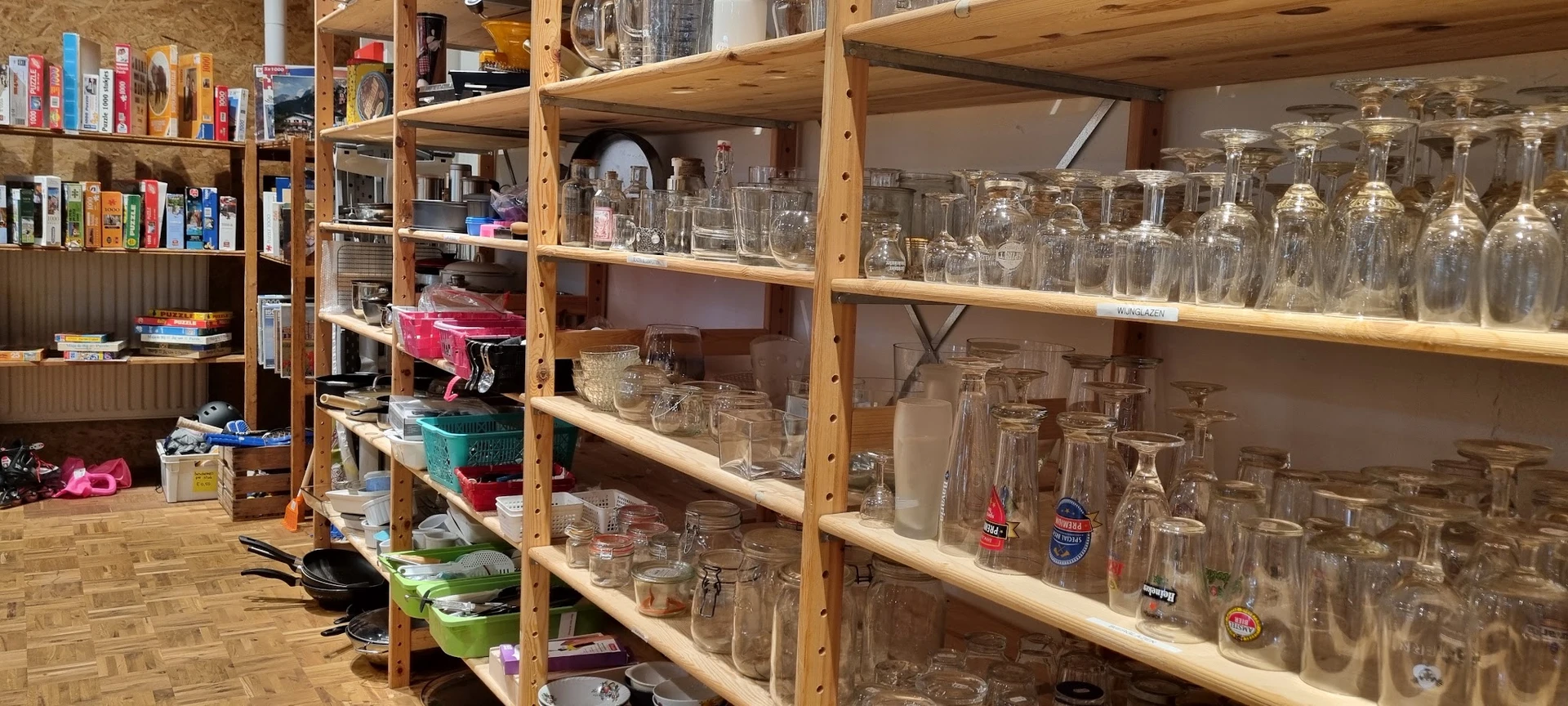 Houten stellingen vol glazen en drinkglazen van verschillende soorten en maten