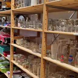 Houten stellingen vol glazen en drinkglazen van verschillende soorten en maten