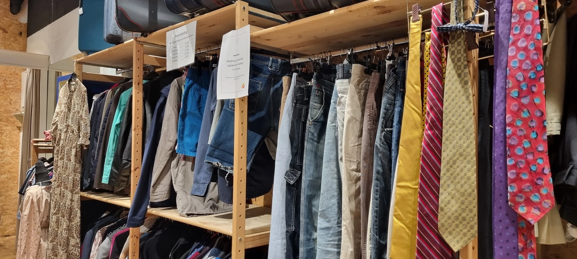 Houten stellingen met tweedehands broeken, jeans en andere kleding aan hangers