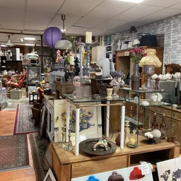 Winkelvloer met diverse meubels, serviesgoed, decoratie en overige spullen uitgestald op tafels en in kasten