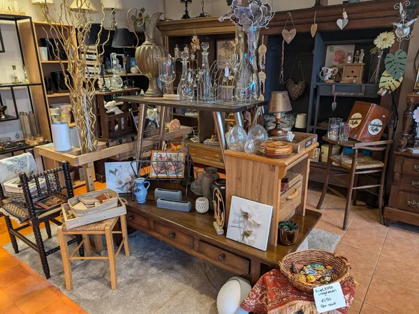 Winkelvloer met houten tafels vol met decoratieartikelen, glazen, kristallen, lampen en diverse inrichtingsspullen