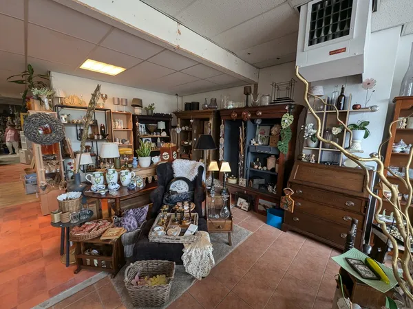 Winkelvloer van kringloopwinkel met verschillende afdelingen, stellingen vol spullen, meubels en decoratieartikelen