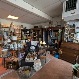 Winkelvloer van kringloopwinkel met verschillende afdelingen, stellingen vol spullen, meubels en decoratieartikelen