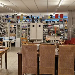 Winkelvloer met tafels, stoelen, kasten en stellingen vol met tweedehands spullen en een versierde kerstboom